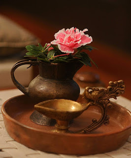 Pink flower on brass kettle and brass diya