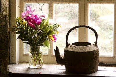 A flowers and kettle decorated on the window sill