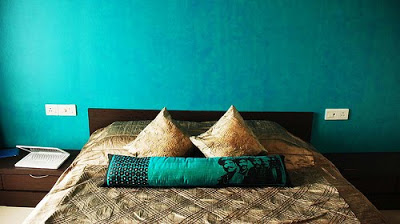 Aqua texture wall, custom made low bed in dark wood & aqua cushion from Good Earth