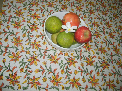 the blockprinted tablecover and bowl of fruits on dining table