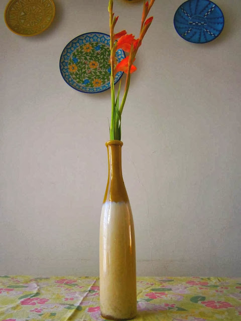 ceramic vase juxtaposed against jaipur blue pottery on wall