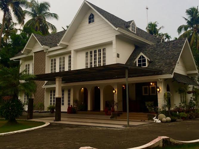 A pristine white house stands tall and stately, with giant coconut trees in the backyard looming over the rooftop | Joseph home tour