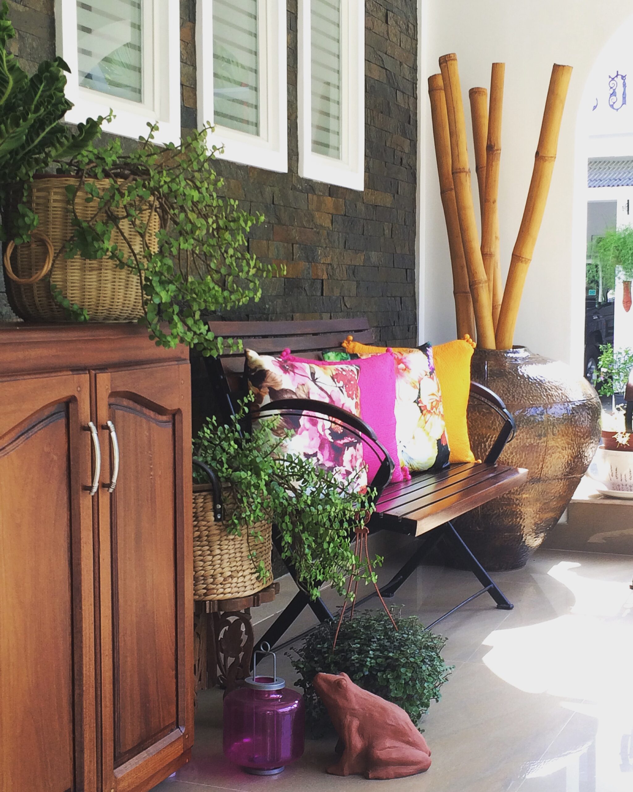 The wooden bench adds drama to the space with its assortment of cushion covers, green touches and garden accessories | Joseph home tour