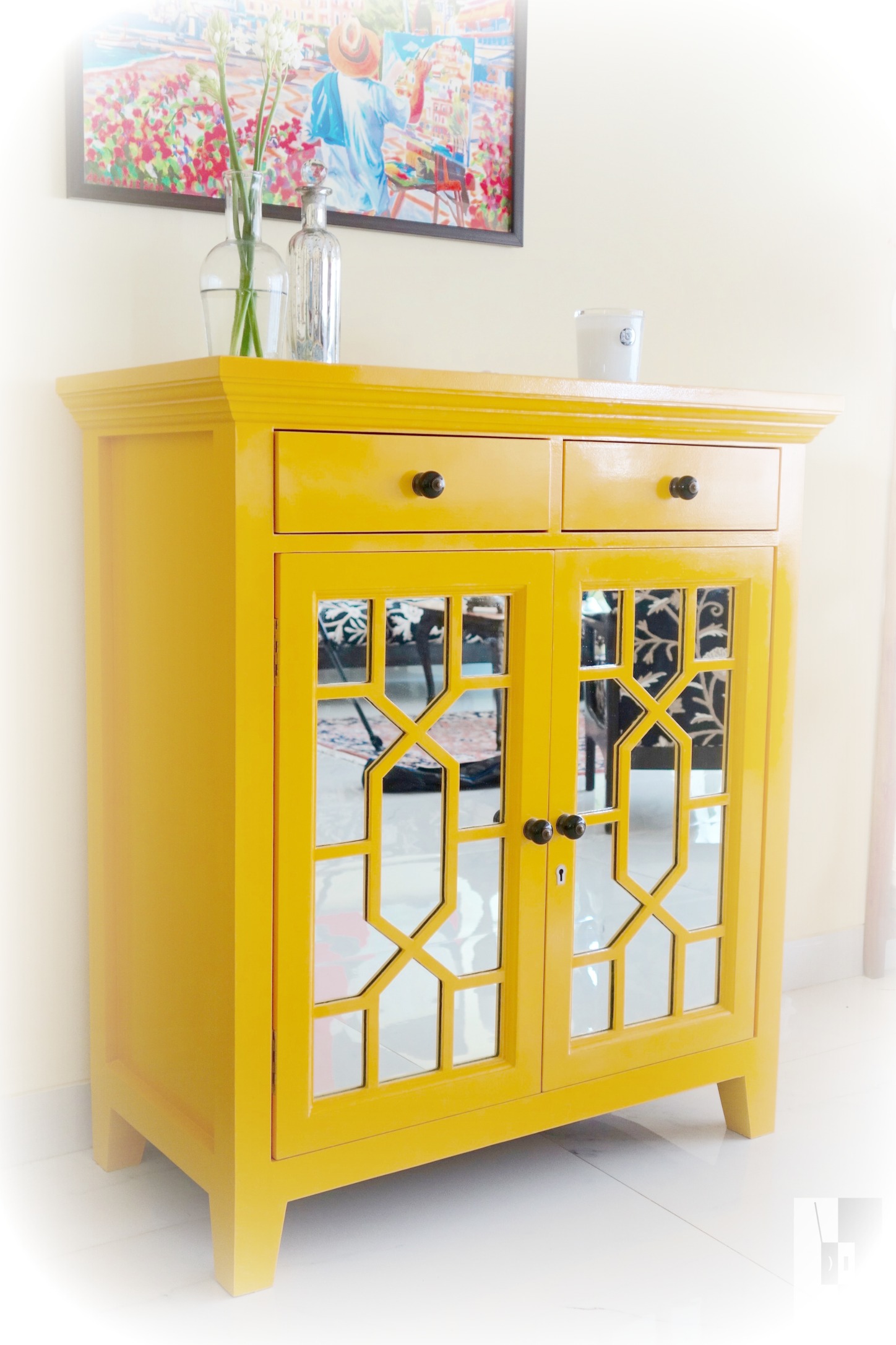A beautiful yellow bar design with a classic glossy oil paint finish and mirror-front doors with art-deco inspired detailing