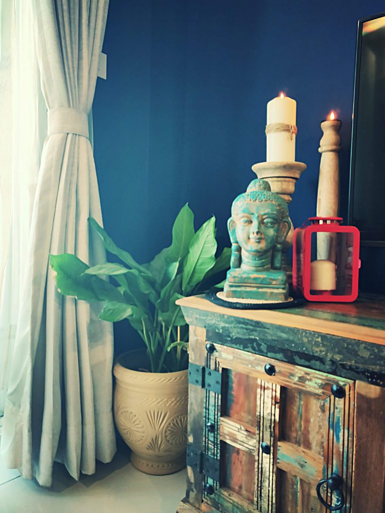 Home style Tour with Rajni in Hyderabad: the collection of buddha statue, candle stands on the drawer and green plants makes the room beautiful
