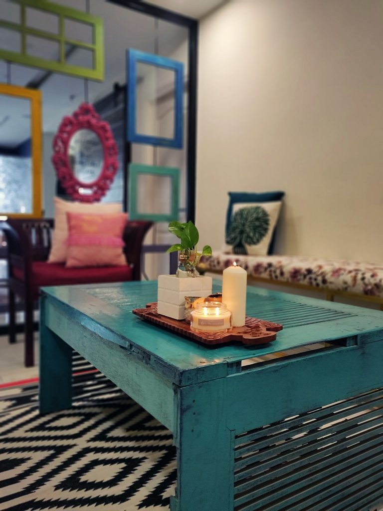 Home style Tour with Rajni in Hyderabad: the living room is filled with beautiful colorful frames, long bench, seater sofa, green plants and candle on table