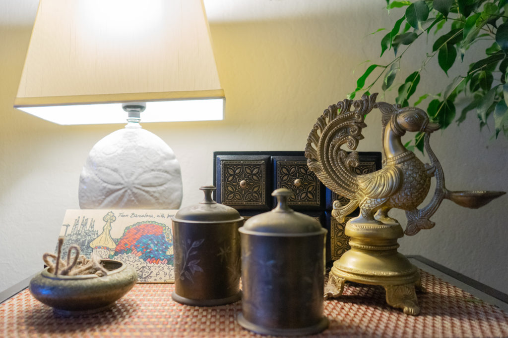 Affinity for antiques and collection of vintage | Home tour of Rushika & Dipkal's - the collection of green plant, lamp, bronze, brass bowl and diya at the corner of the living room