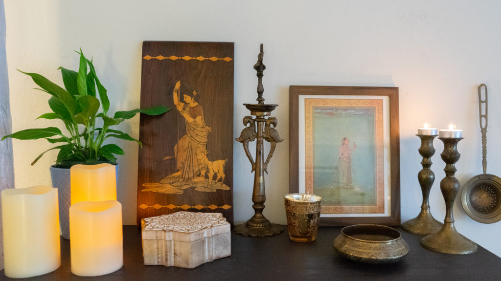 Affinity for antiques and collection of vintage | Home tour of Rushika & Dipkal's - the beautiful collection of candles, frames, brass bowl, green plants, candle stands, and diya at the corner of the room