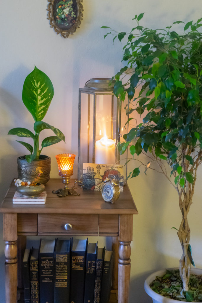 Affinity for antiques and collection of vintage | Home tour of Rushika & Dipkal's - the collection of brass bowl, antique clock, lantern, candle stands and green plant on the table