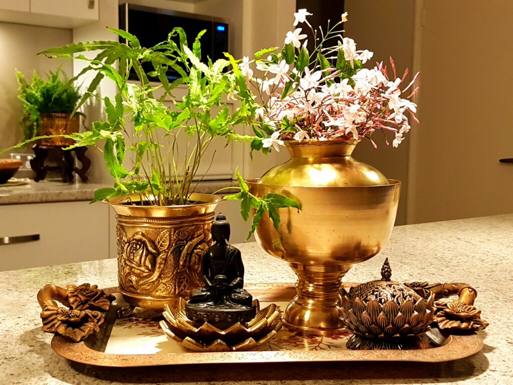 The table is setting up with fresh flowers and green plant in a brass-vase
