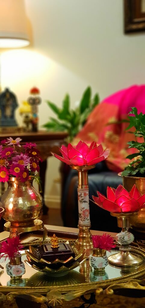 The table in the living room is setting up with fresh flowers, lotus candle stand and brass collection on it