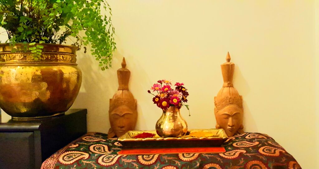 Fresh flowers, buddha wood sculpture and green plants at the corner of the room