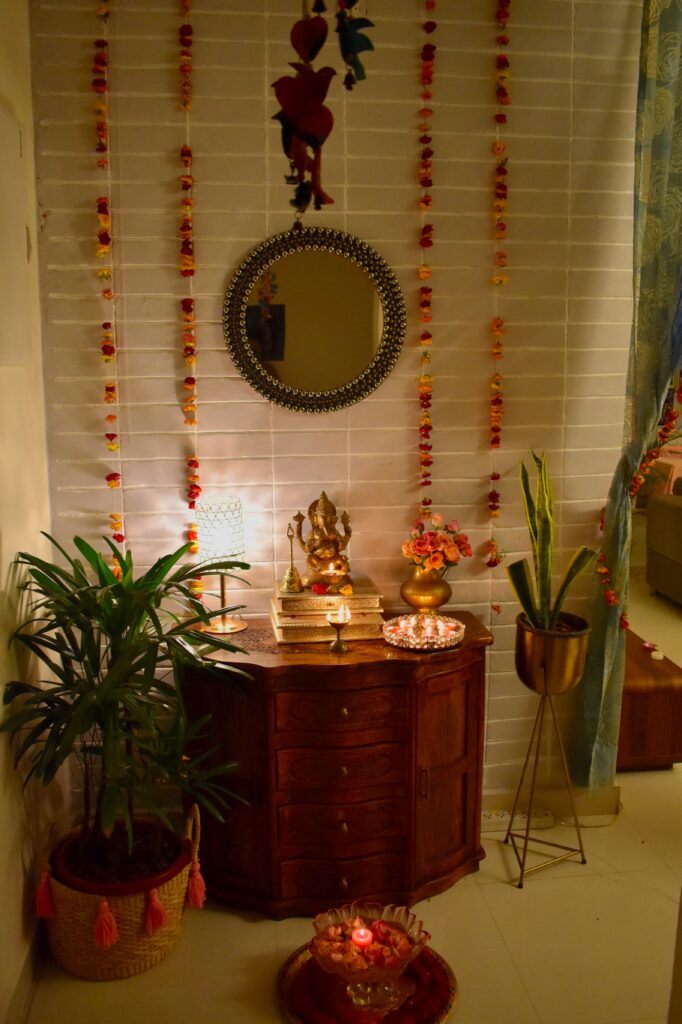 the pooja room is decorated with fresh flowers, lamp, diya, ganpati and green plants