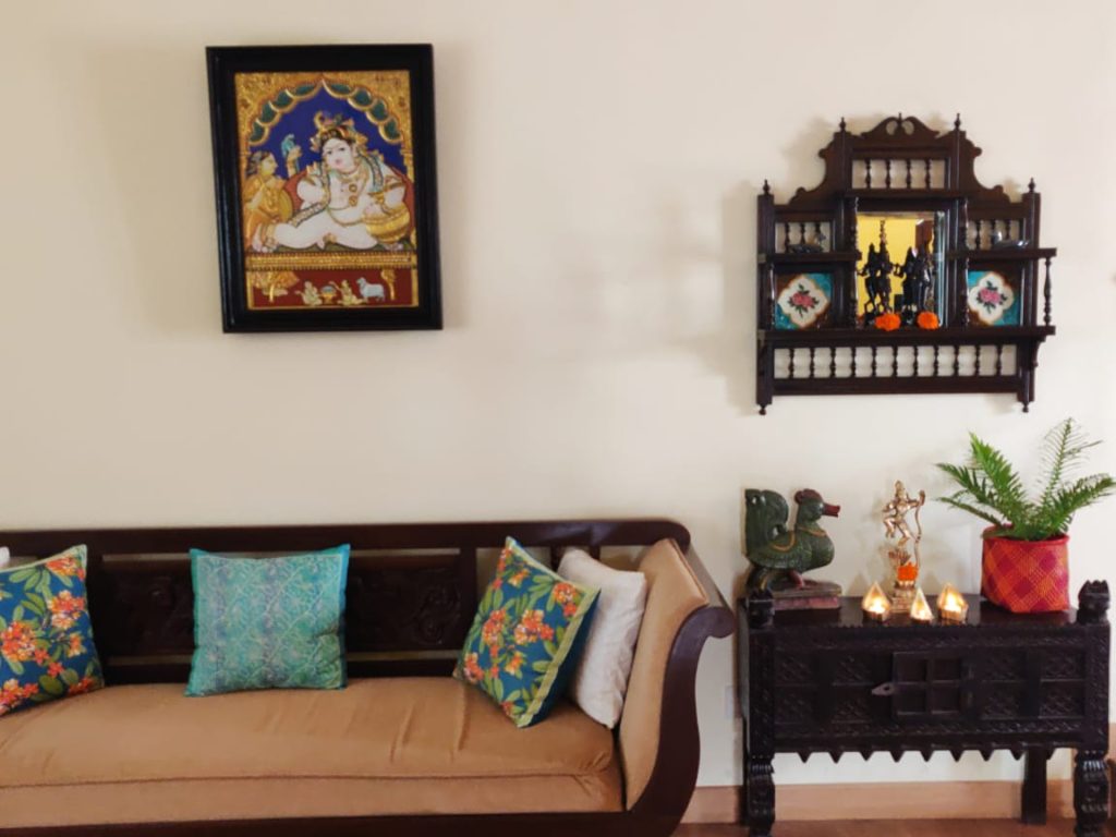 The vintage mirror, wall frame, diyas, green plants and sculpture at the corner of the living room