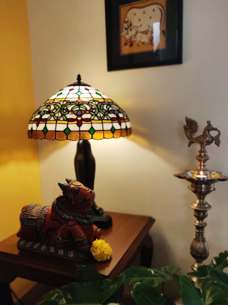 diya brass, lamp, bull sculpture, pichwai frame and green plants decorated at the corner of the living room