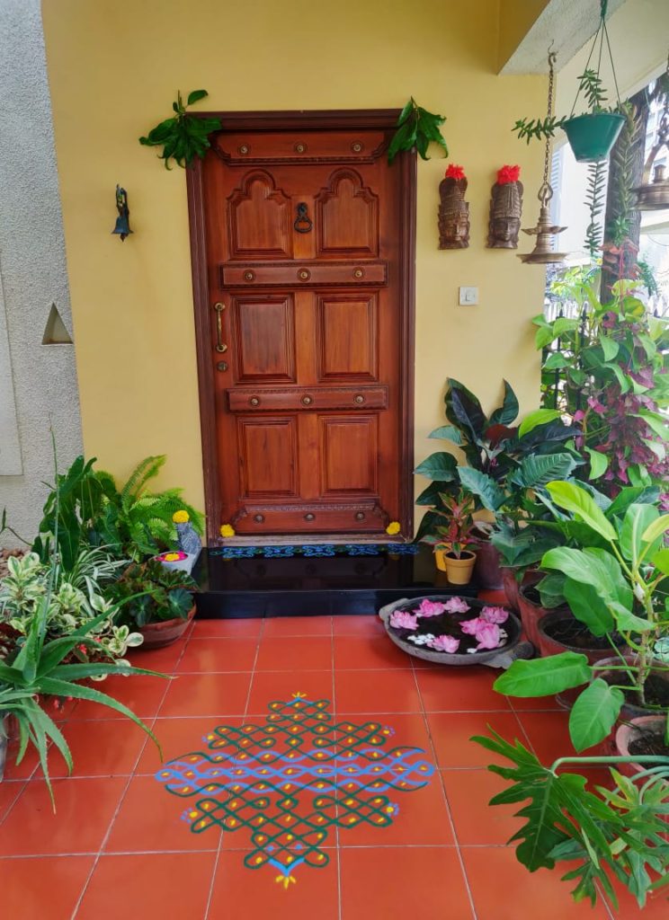 the beautiful indoor and outdoor green spaces, hanging brass diyas, mask wall decor and rangoli at the front door