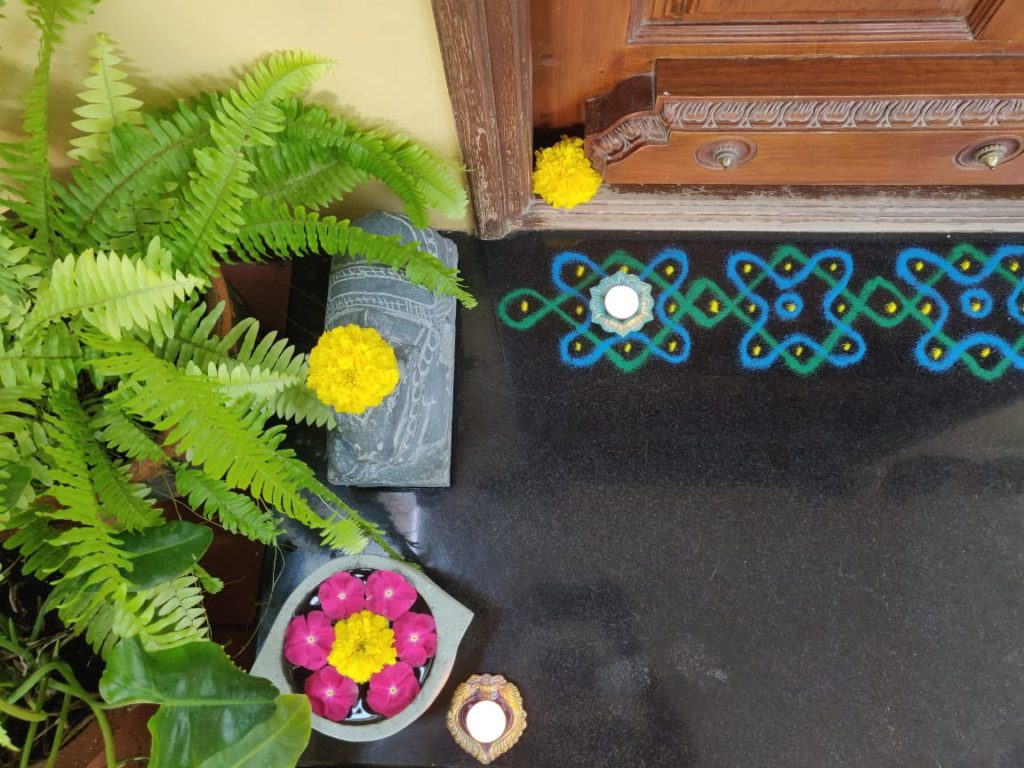 rangoli powder design and fresh flowers rangoli decorated at the front door entry