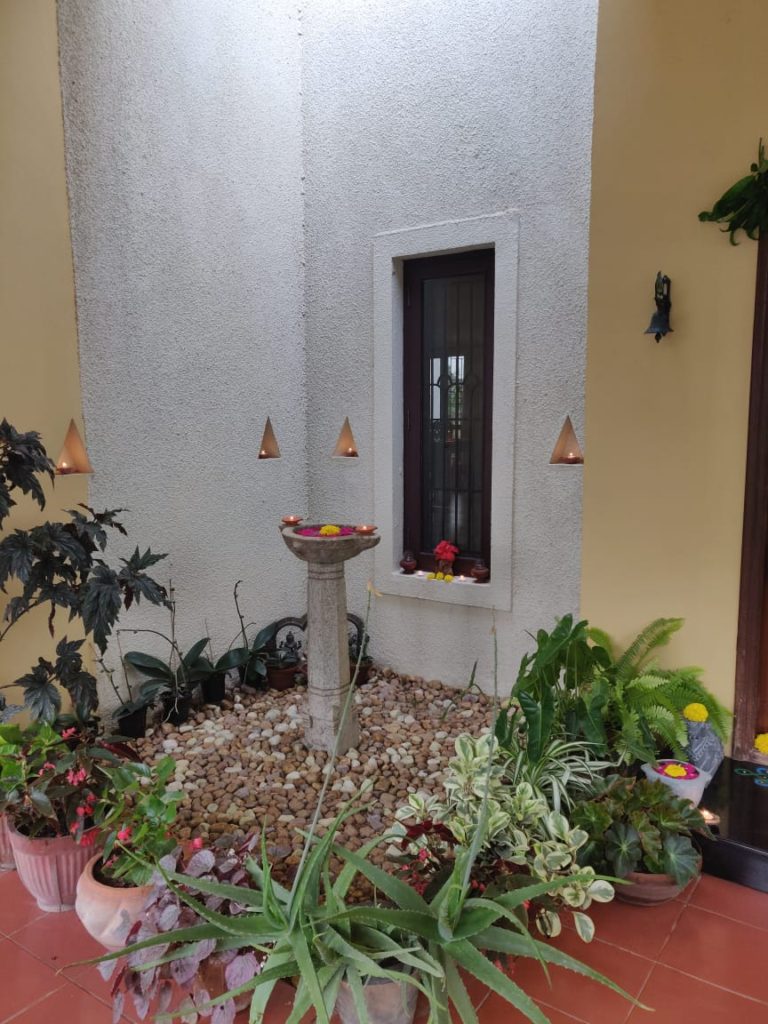 diyas, green plants and fresh flower rangoli at the corner of the front door entry