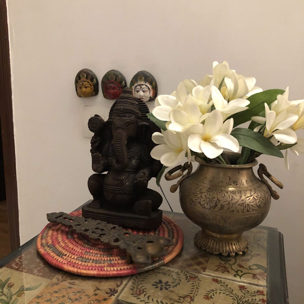 the top table is decorated with little fabric squares displayed under the glass, ganesha, fresh flowers on brass vase and brass spoon | Vintage Modern Indian decor | theKeybunch decor