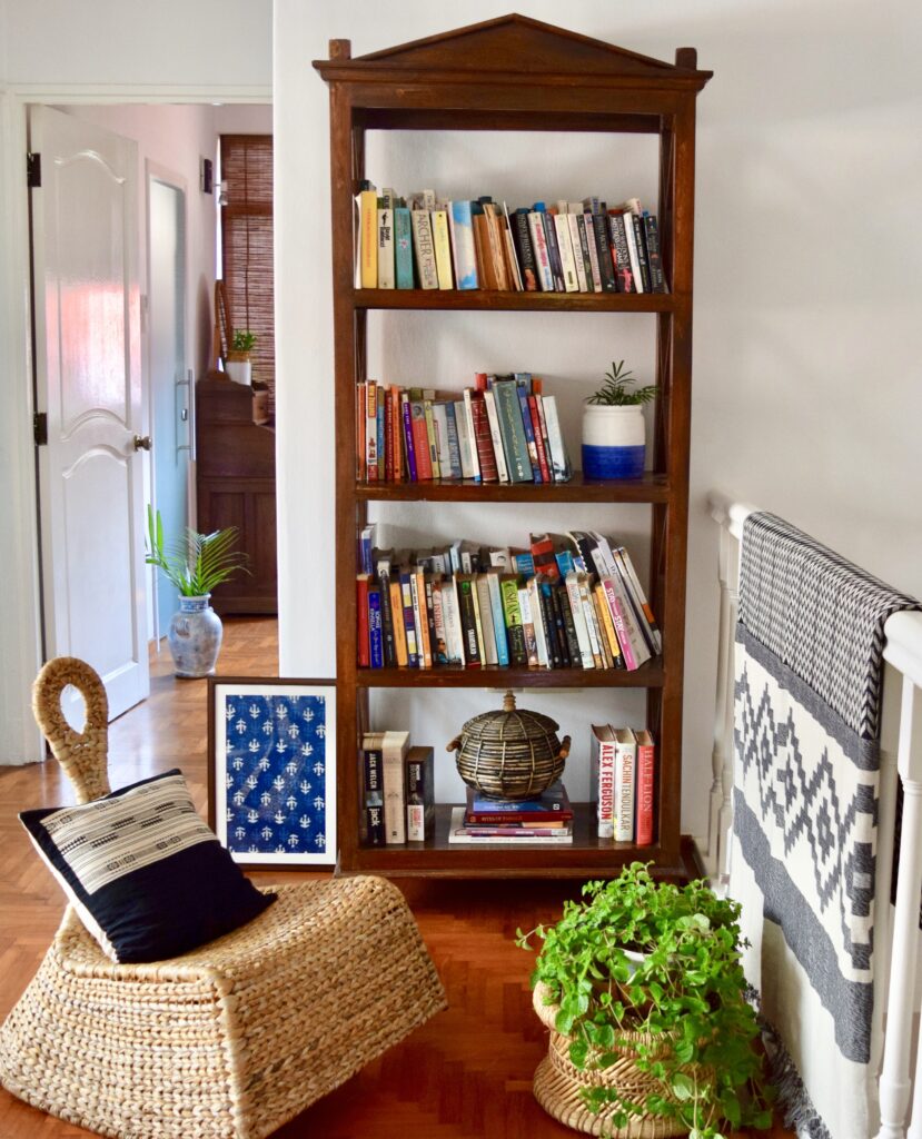The reading room is decorated with bookshelf, green plants and rattan furniture | ASHA RAJ home tour