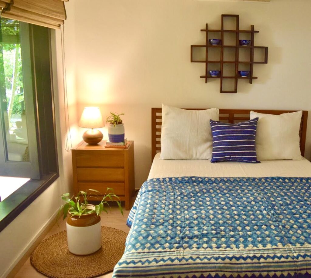 The guest bedroom is decorated with wall shelf, green plants and a lamp at the corner of the room | ASHA RAJ home tour