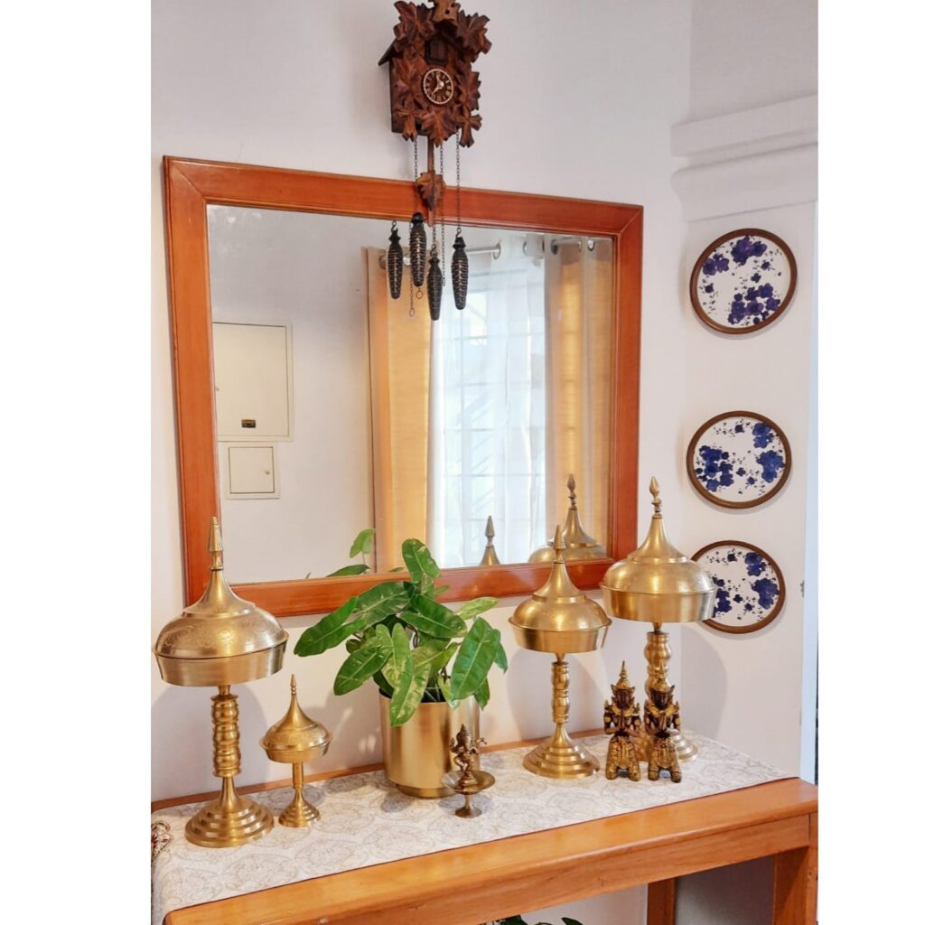 A traditional Assamese bell metal piece, green plant, brass collection, wall decor and mirror at the corner of the room | Upasana Talukdar home tour | thekeybunch decor 