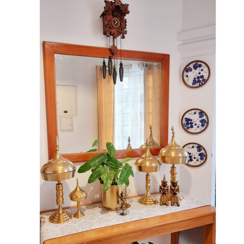 A traditional Assamese bell metal piece, green plant, brass collection, wall decor and mirror at the corner of the room | Upasana Talukdar home tour | thekeybunch decor