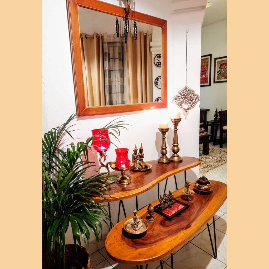 the corner of the room is decorated with brass collection, green plant, mirror view and wooden table | Upasana Talukdar home tour | thekeybunch decor