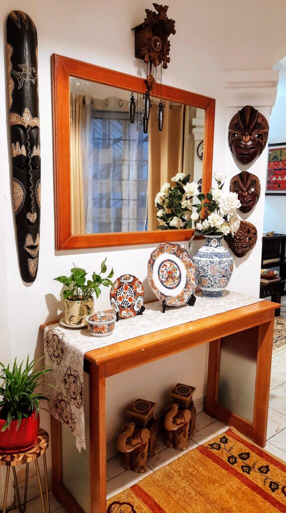 the corner of the room is decorated with a traditional Assamese bell metal piece, wall mask, green plant, decorative plates and a beautiful porcelain vase | Upasana Talukdar home tour | thekeybunch decor