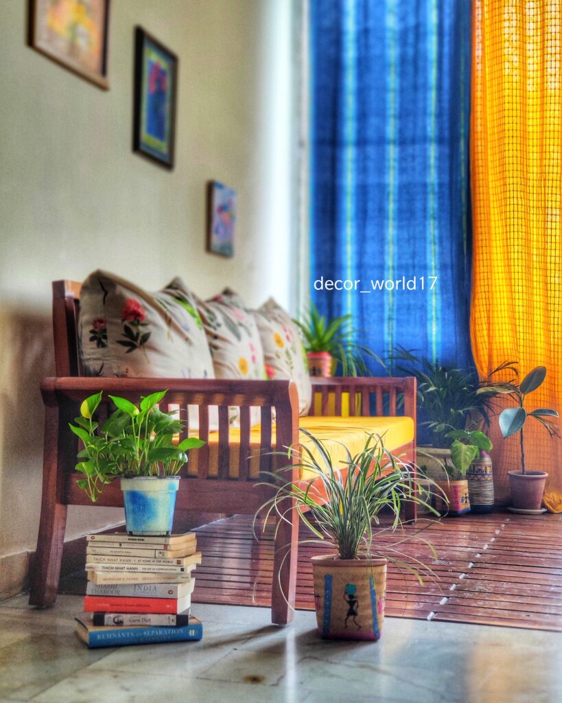 The stack of books, colorful curtains, green plants, wall frames, and antique chair at the corner of the room | Dharitri home tour | thekeybunch decor