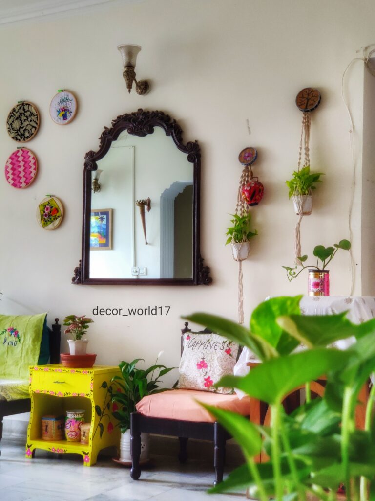 The corner of the room is decorated with antique chairs, yellow table, green plants, decorative mirror and wall decor | Dharitri home tour | thekeybunch decor