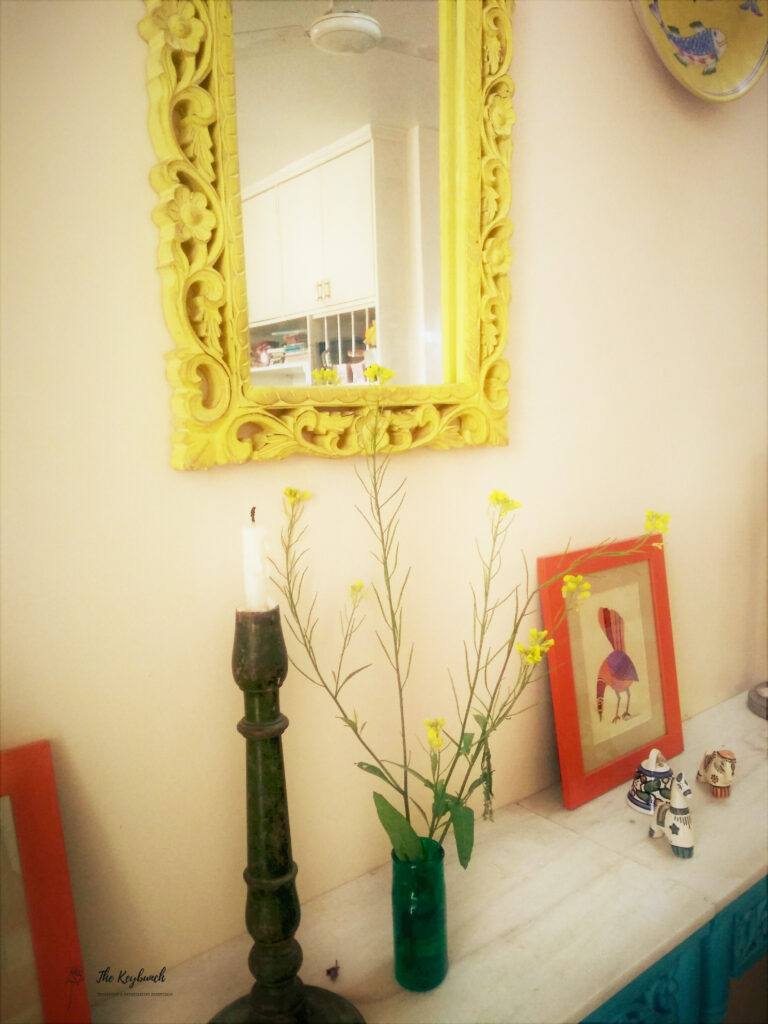 The corner of the room is decorated with yellow mirrored frame, green candle stand, plant and frame | Areas where an Interior Stylist can help you | Thekeybunch decor blog