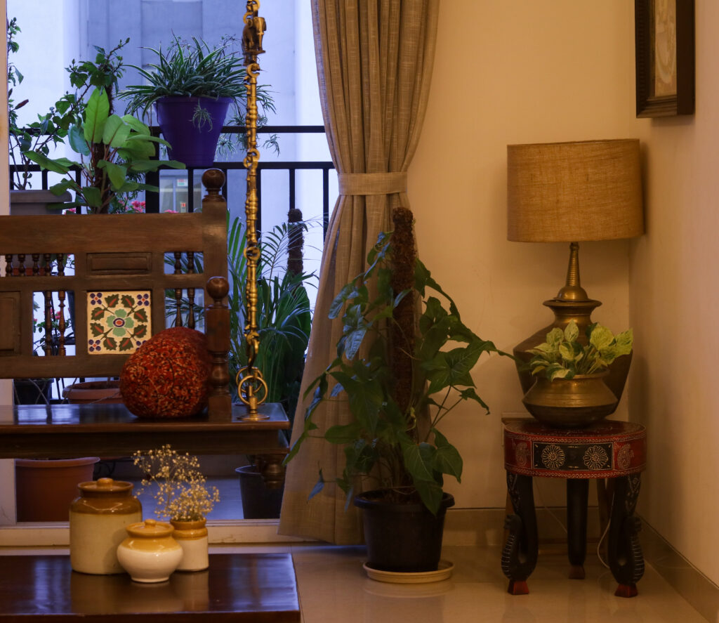 A swing set, green house plants, brass table lamp are decorated in living room | Home Tour: A beautiful Antique Modern home in Bangalore