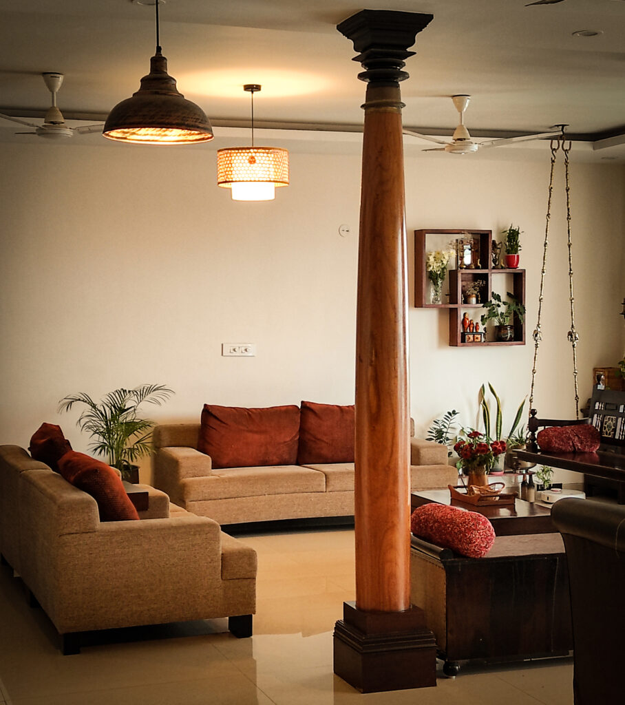 8ft pillars from Tamil Nadu, traditional jhoola swing, and green plants decorated in living room | Home Tour: A beautiful Antique Modern home in Bangalore