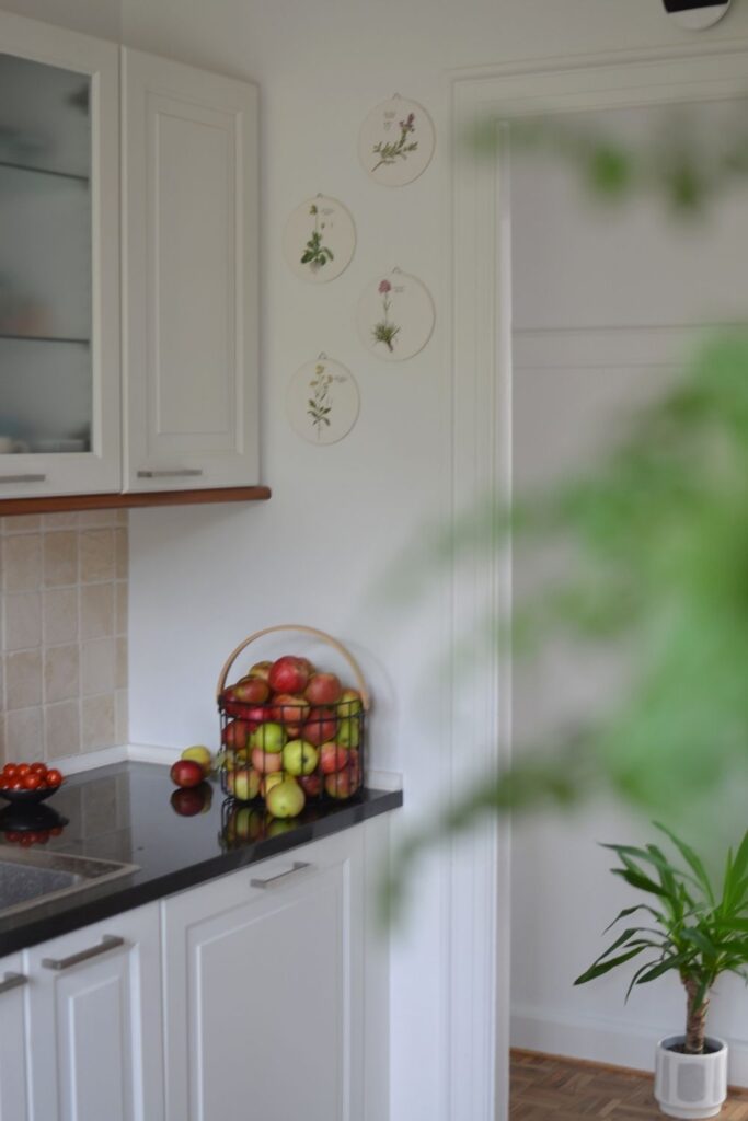 The black metal basket is filled with home grown apples and floral wall plates at the corner of the kitchen | Naina's Scandi-Minimalist Home with Indian Accents