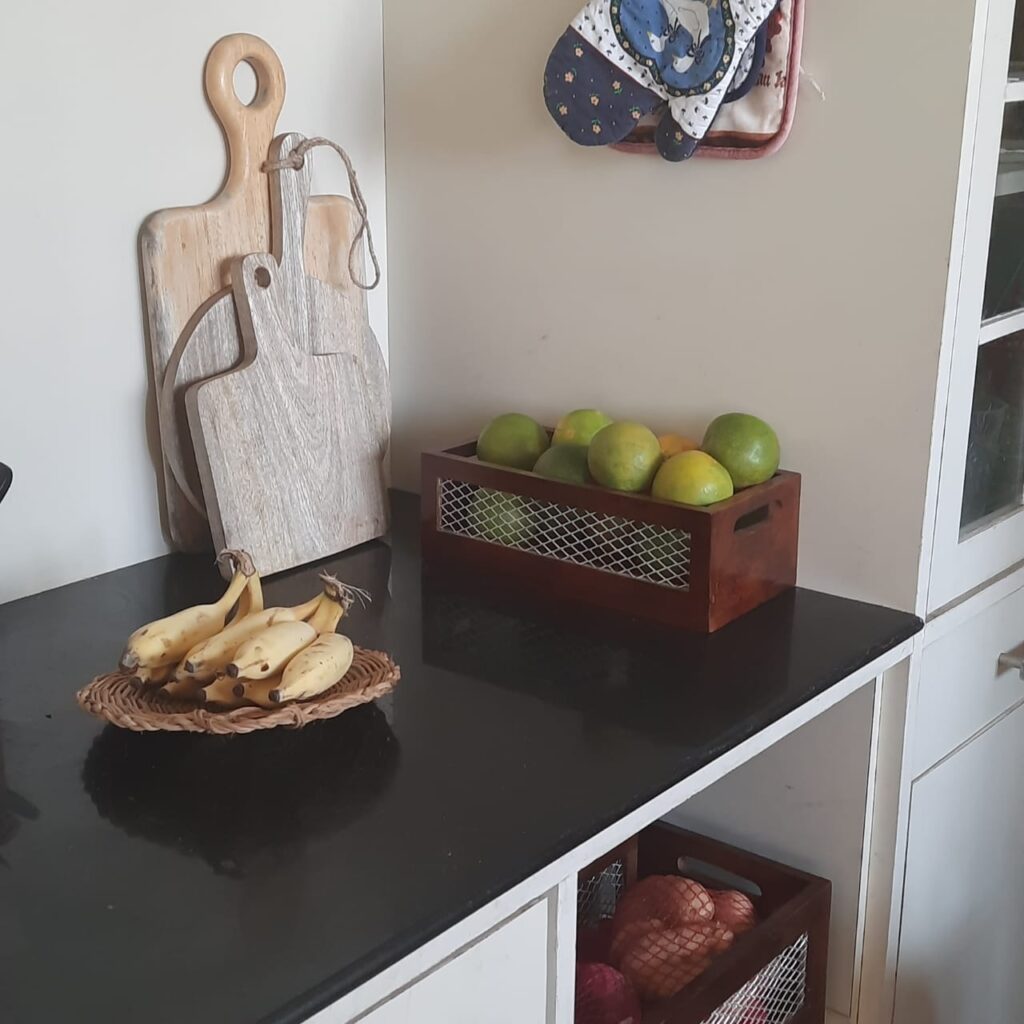 The kitchen filled with a flat woven plate to hold the bananas, handmade chopping or cheese board and baskets filled with fruits and potatoes | A case for Baskets | TheKeybunch decor blog