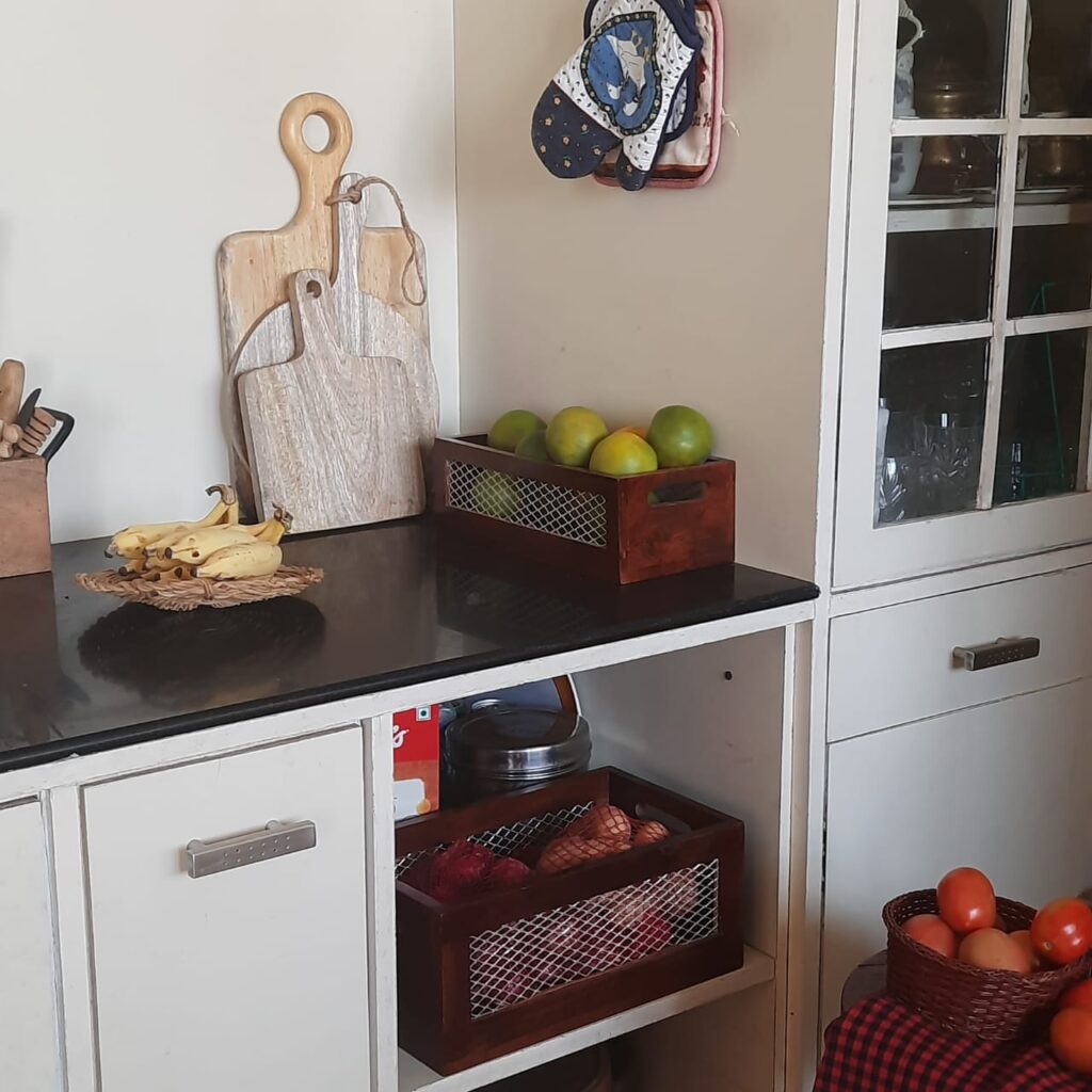 The kitchen filled with a flat woven plate to hold the bananas, a round dark cane basket to hold the tomatoes, propped on the stool, chopping or cheese boards, and of course the baskets of produce | A case for Baskets | TheKeybunch decor blog