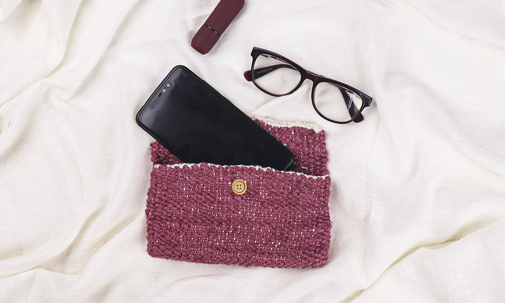 a hand clutch with a mobile fitting in, and spectacles close by | 6 Tapestry DIYs on Muezart's home-use loom