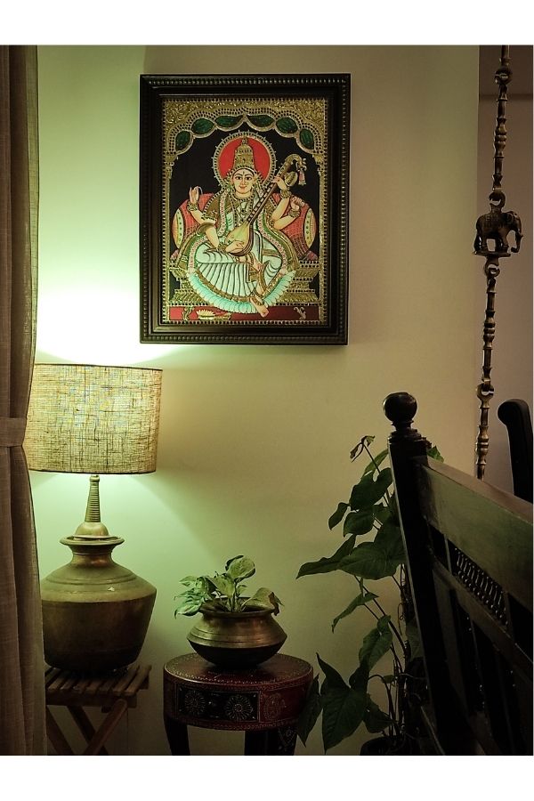 The tanjore paintings, brass table lamp, brass vase and green plants at the corner of the living room | Home Tour: A beautiful Antique Modern home in Bangalore