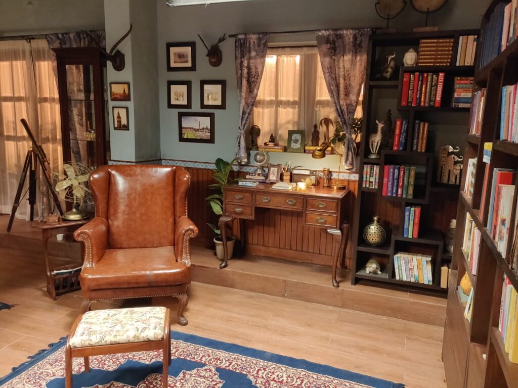 Villa Rashmi - A Heritage Gem in Mumbai | Wing chair, vintage books on wooden shelf and console table at the reading room | TheKeybunch decor blog