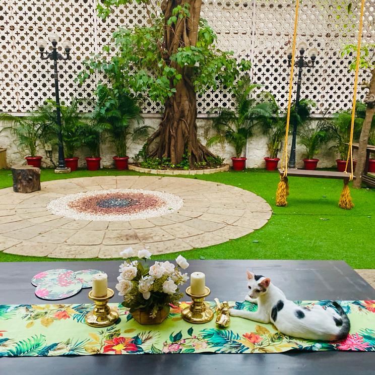 Villa Rashmi - A Heritage Gem in Mumbai | The table runner was decorated with fresh flowers, candle stand holder and a cute cat in the backyard garden | TheKeybunch decor blog