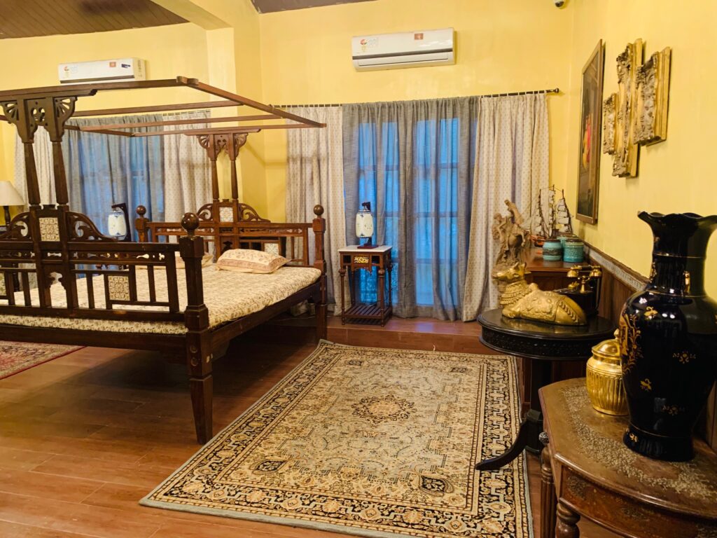Villa Rashmi - A Heritage Gem in Mumbai | Traditional Indian bed with lamp on side table, wall frames and vintages decorated at the bedroom | TheKeybunch decor blog