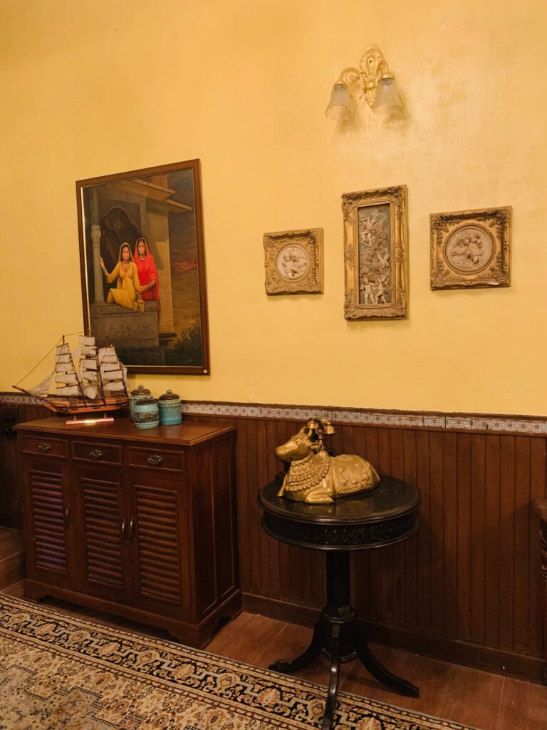 Villa Rashmi - A Heritage Gem in Mumbai | The bedroom corner was decorated with wall frames, vintages on top of wooden cabinet and brass nandi statue on top of the table | TheKeybunch decor blog