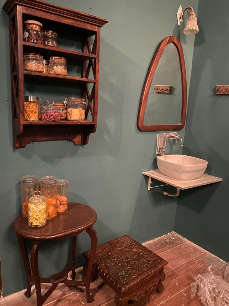 Villa Rashmi - A Heritage Gem in Mumbai | Wooden shelf, antique wooden table and stool, unique mirror and wash basin at the corner of the kitchen | TheKeybunch decor blog