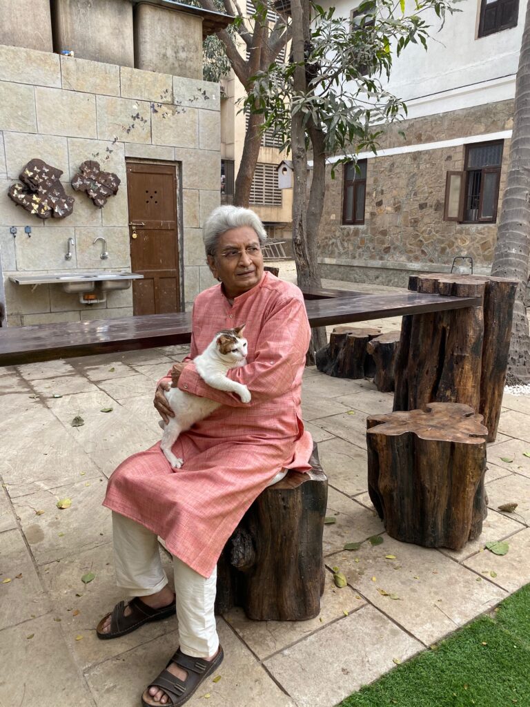 Villa Rashmi - A Heritage Gem in Mumbai | Haresh Patel sitting on wooden tree stump stool at the backyard of the villa | TheKeybunch decor blog