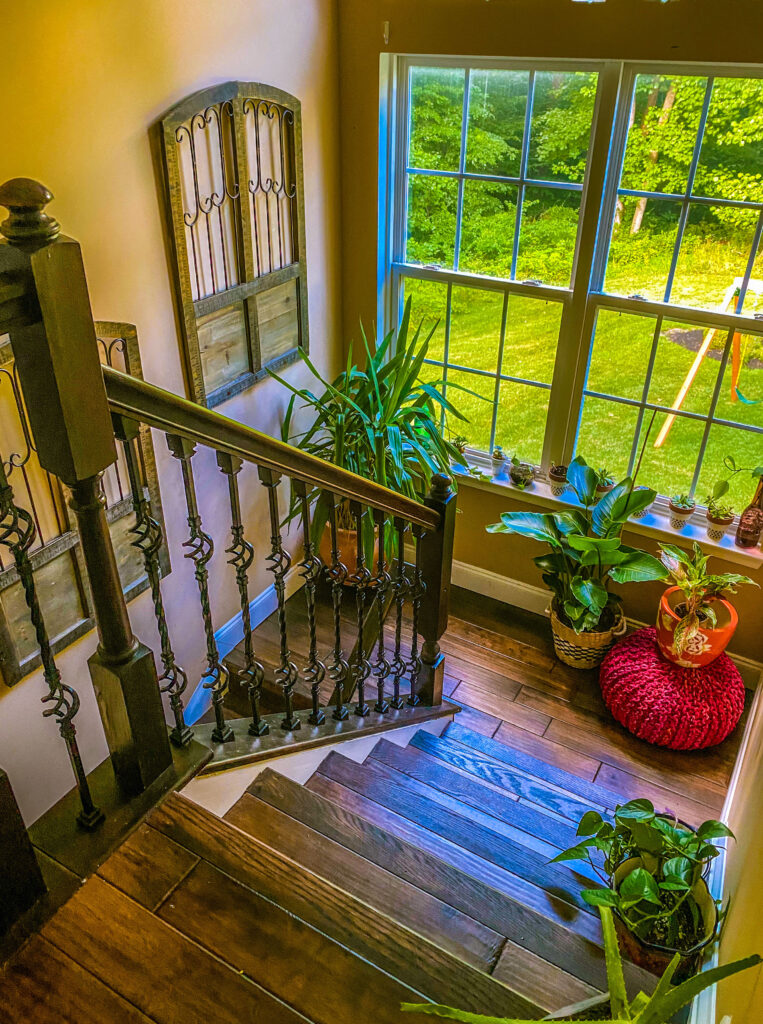 Chitra's Joy-Infused Boho Eclectic home | The beautiful stairway and decor, clear glass window and outdoor view of garden