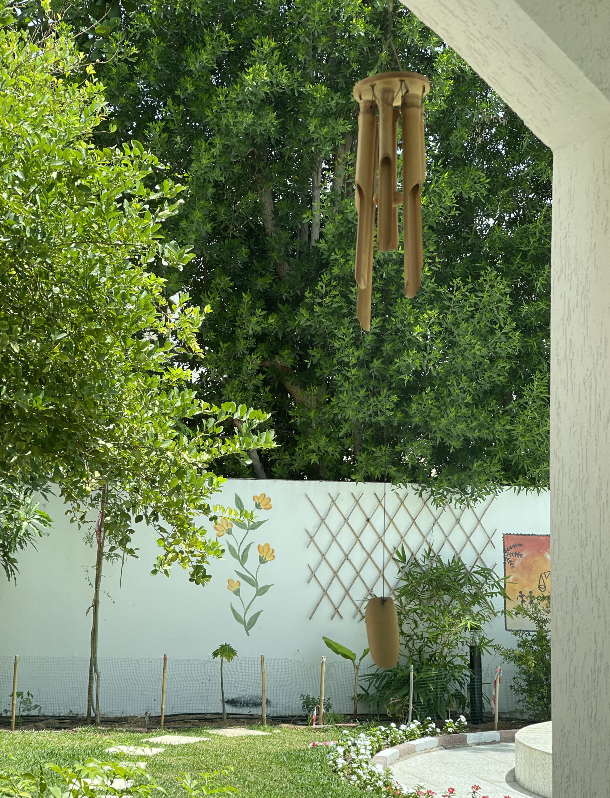 Prameela Nair's Art-Infused Home Abudhabi | Brass wind chimes hanging in garden