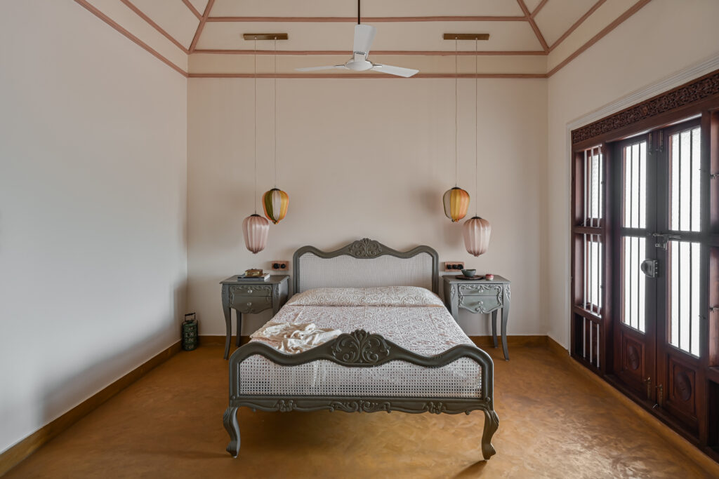 Raja’s Cottage - A traditional Mangalore home with a Chettinad Flavour | a carpet tiled patch made with printed tiles in front of the bed, and a carved bed with a hint of cane with matching side tables