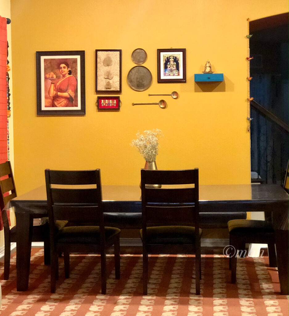 Home tour of Meena Harish | The dining wall has been decorated with Ravi Varma’s Maharashtrian lady, Preserved Peepul tree leaves, Jamini Roy painting on a serving tray, Brass plates, Brass ladles, Goddess of food – Annalakshmi on Tanjore painting and the Annapoorani brass statue.
