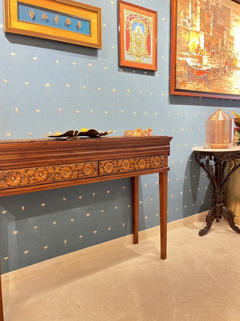 Console table, unique bird diya with brass thali, vintage copper water and the mudras in the entryway gallery wall | Ranjana and Milind's apartment in Pune